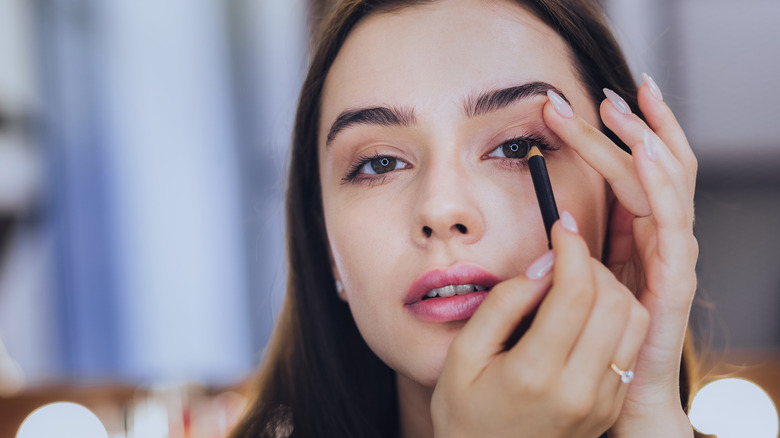 woman applying eyeliner pencil
