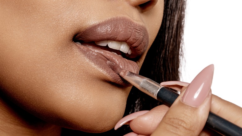 woman applying lipstick with a brush