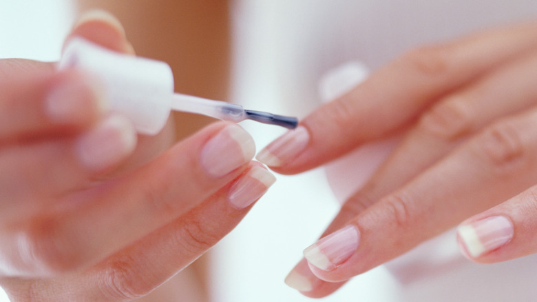 Person applying nail treatment to healthy natural nails