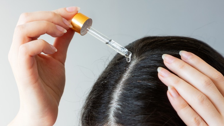 woman adding drops to hair part