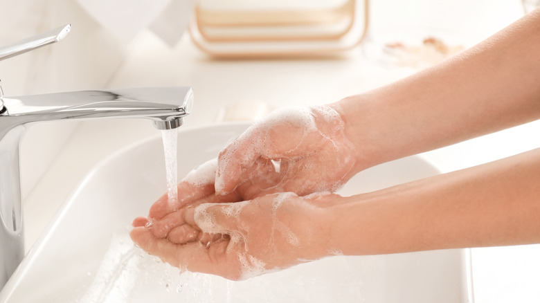 woman washing hands with soap and water