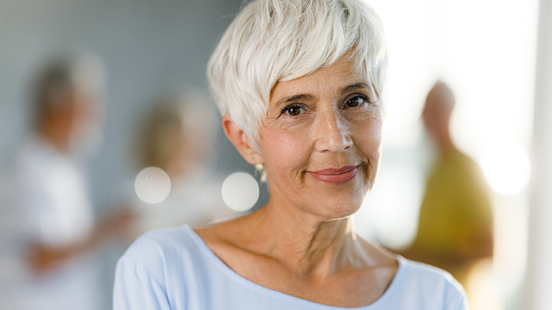 A beautiful older woman with a soft pixie smiling at the camera while posing for a picture