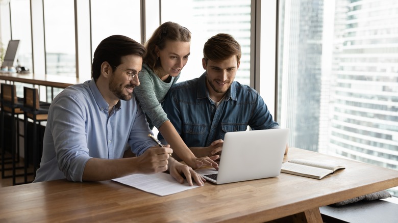 employees looking at laptop and talking