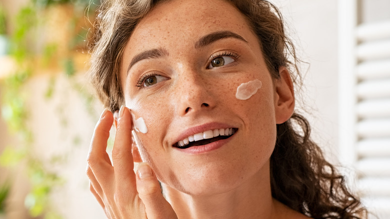 woman applying moisturizer on face