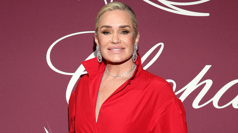 Yolanda Hadid awith full, thick eyebrows and a gorgeous red dress posing at the Cannes Film Festival