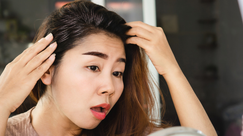 Woman examining gray hair stemming from her roots
