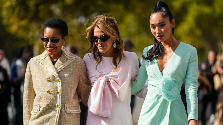 Three women wearing passive colors like light beige and pastels