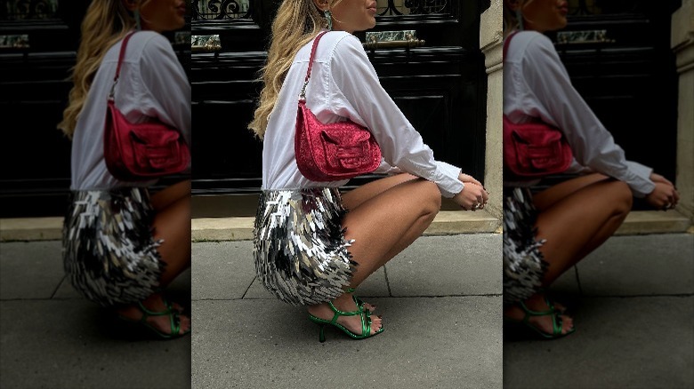 woman squatting wearing silver skirt and white button up 