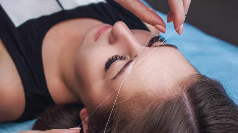 women getting eyebrows threaded