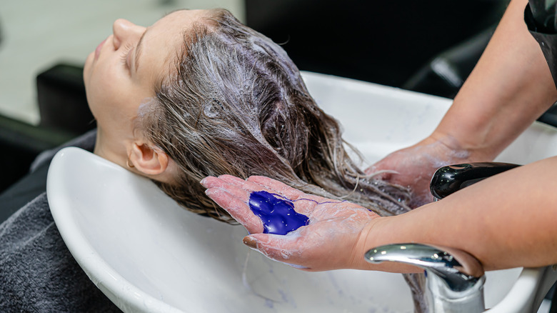 Hairstylist shampoos client's hair