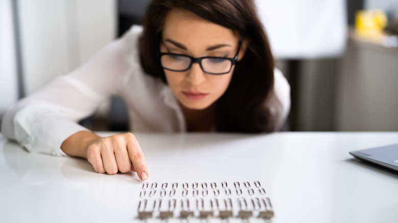 woman meticulously arranging paperclips on table