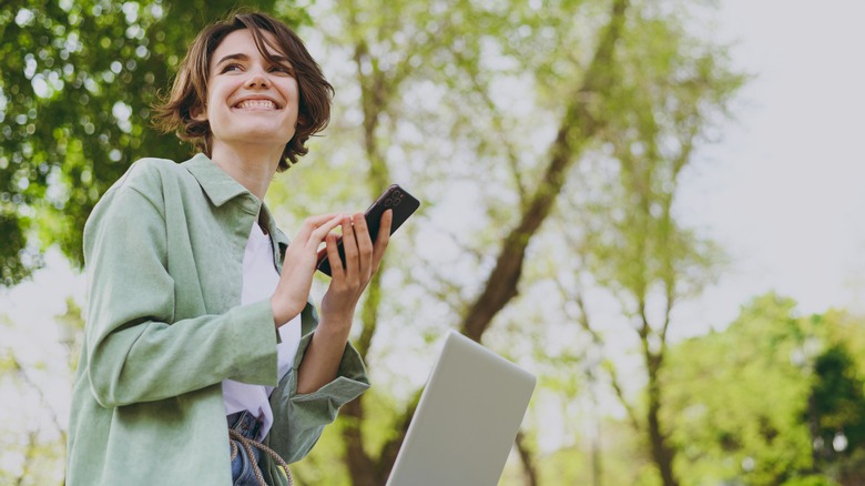 Woman using phone and laptop 