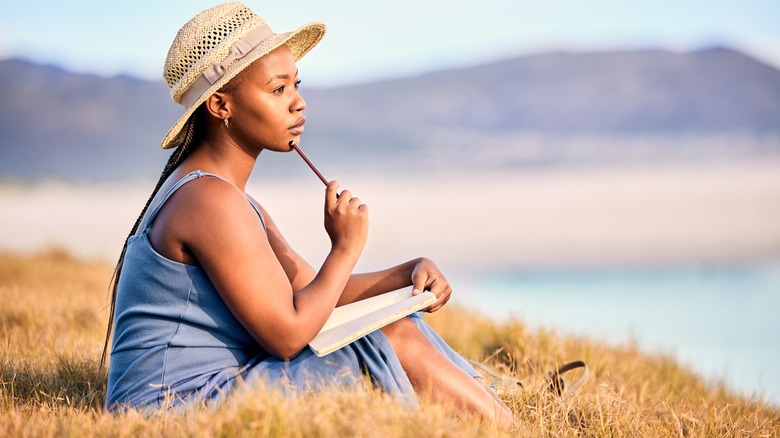 Woman ponders while writing in journal