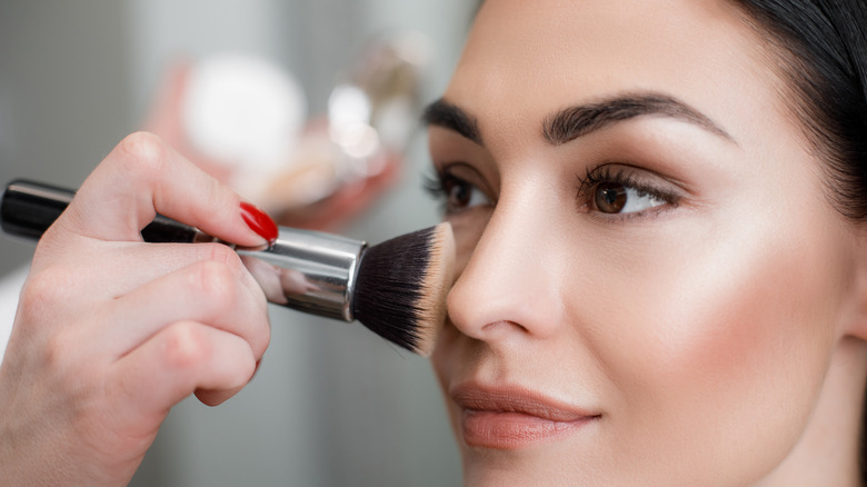 close up of makeup artist applying blush on woman's face