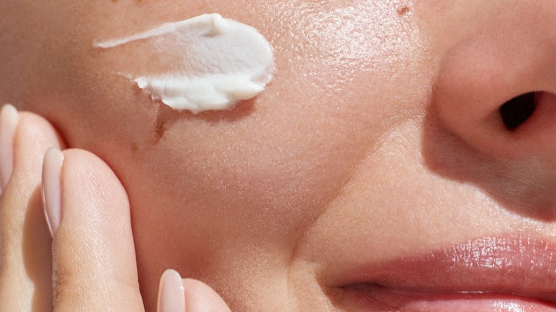 person applying moisturizer on cheek