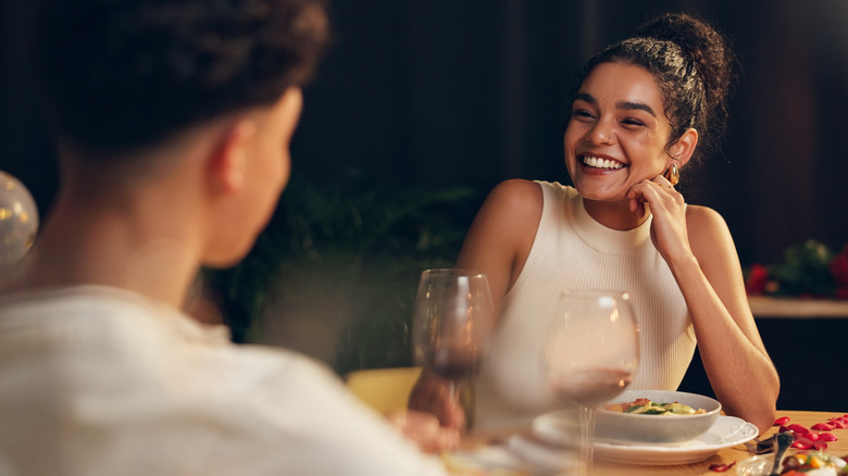 A woman on a date drinking red wine and smiling at her date