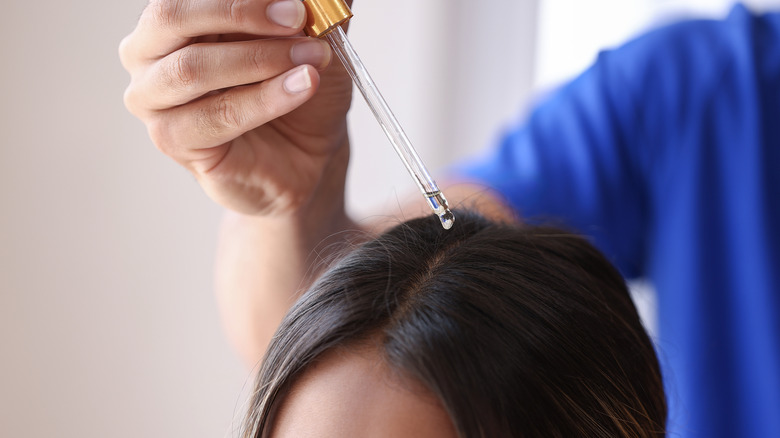 person applying oil to scalp