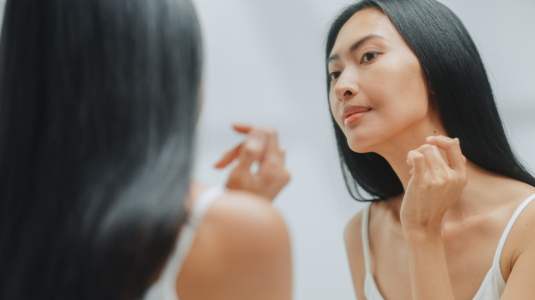 Woman inspects skin in mirror