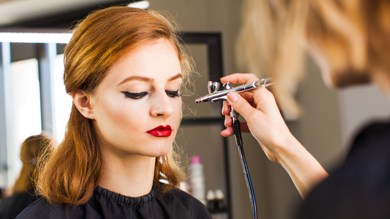 young woman getting airbrush makeup