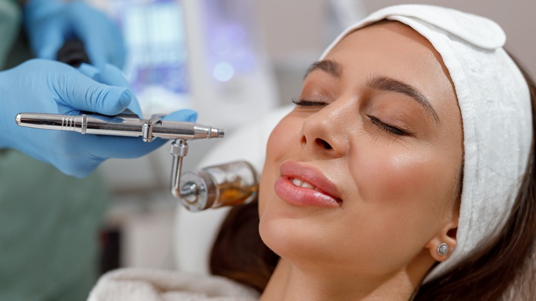 woman getting face airbrushed