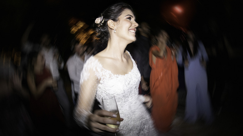 A bride dancing with a drink in her hand