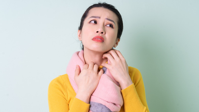 woman itching neck under her scarf