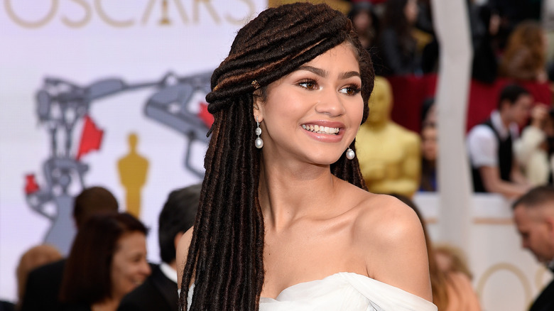 Zendaya smiles while walking on the red carpet of the Oscars in 2015