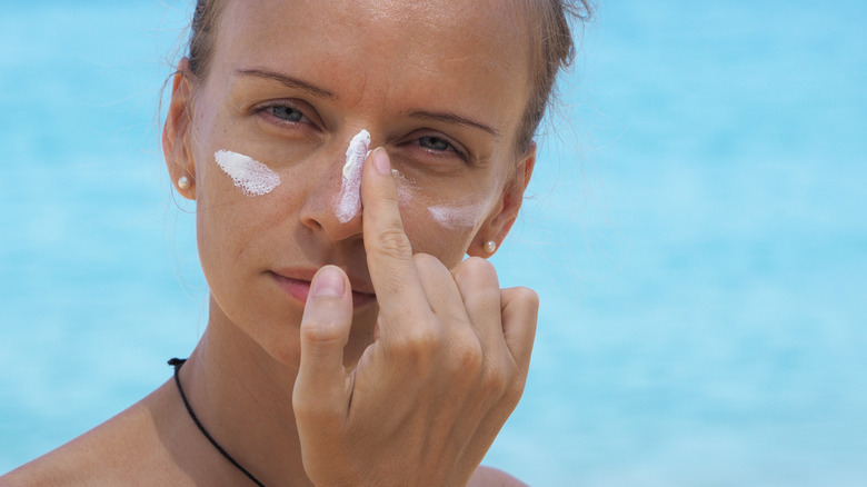 Woman puts sunscreen on face