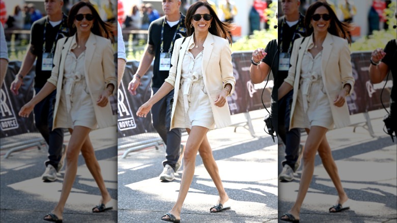 Meghan Markle walking at the 2023 Invictus Games. She is wearing a white blazer with a white shorts jumpsuit and black slides.