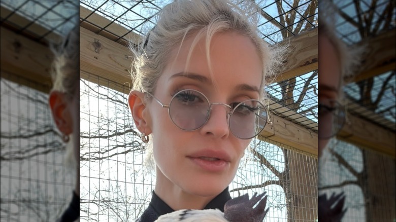 Kelly Osbourne without makeup and her blonde hair tied up. She is wearing a pair of circle-shaped wire framed glasses.