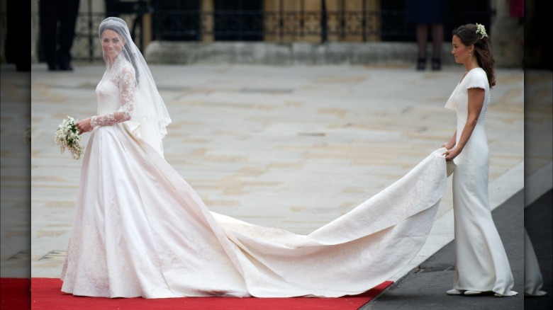 Kate Middleton on her wedding day. This image gives a full view of her gown and its long train. Her thin white veil covers her face
